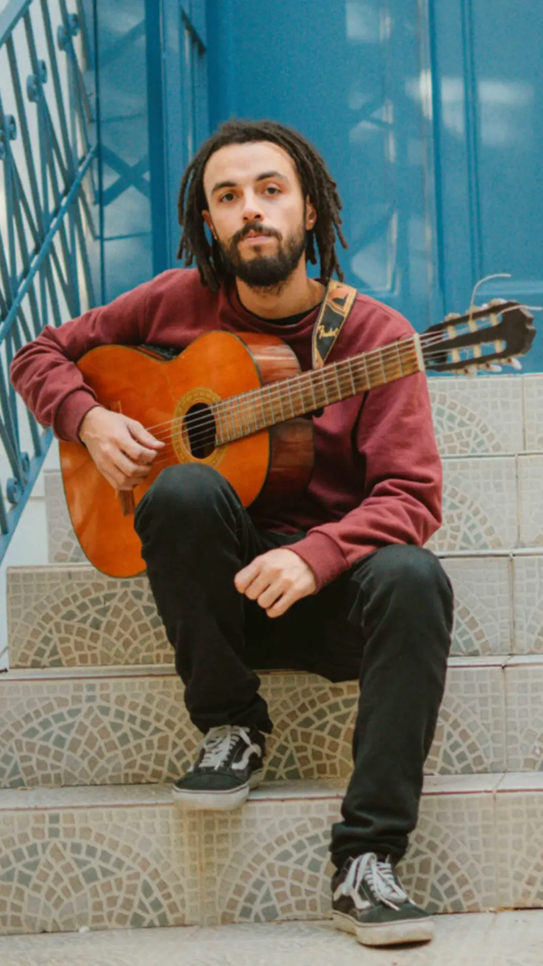 Rodrigo Miranda sentado na escada com o violão